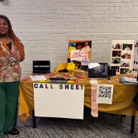 Spirit Destine and Syndic Thomas stand in front of the table they are sharing to display work.